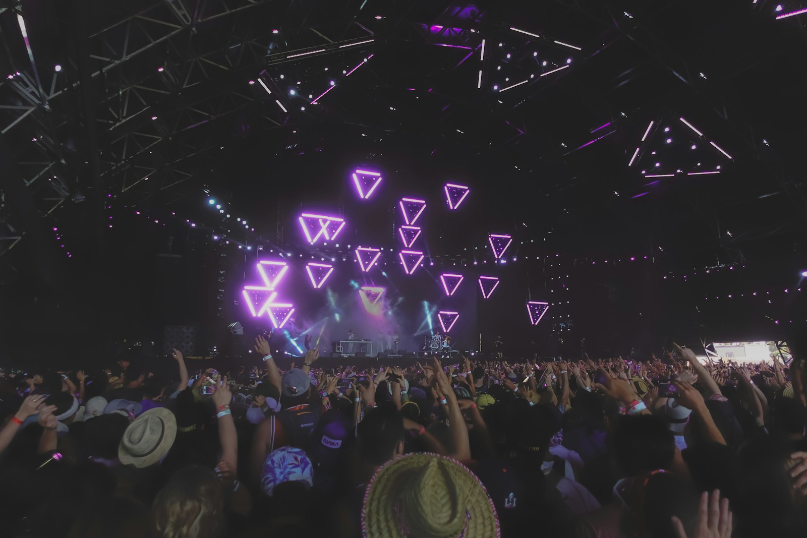Fans watching a festival stage filled with violet geometric lights